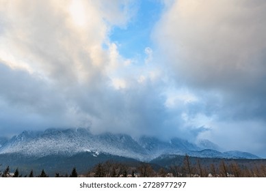 Snow-capped mountain range under dramatic cloudy sky.