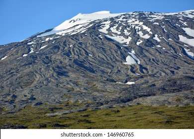 snow-capped mountain and volcanic lava flow  across a field in snaefellsjokul, on a sunny day in snaefellsnes national park,  iceland
