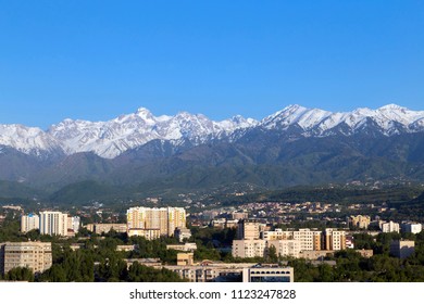 Snowcapped mountains over the city of Almaty in the afternoon. Spring urban landscape.