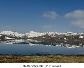 
Snow-capped mountains reflect perfectly in a tranquil lake under a clear blue sky, creating a breathtaking and serene landscape. - Powered by Shutterstock