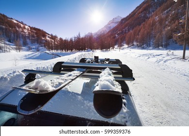 Snowcapped Skis Fastened On Car Roof Rails