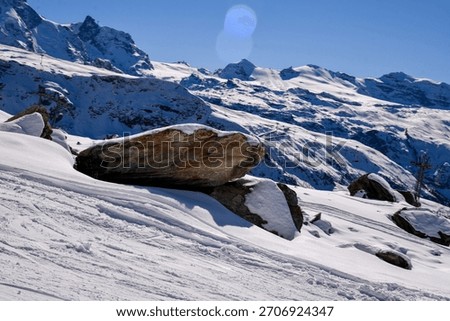 Snow-covered Alpine landscape with dramatic mountain peaks, rocky slope, and untouched winter terrain. Scenic view of the Swiss Alps in bright daylight.