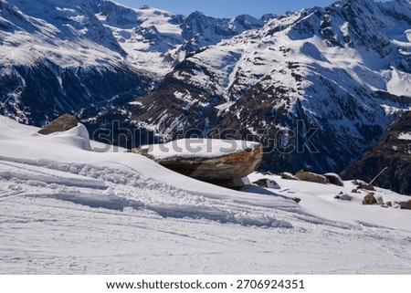 Snow-covered Alpine landscape with dramatic mountain peaks, rocky slope, and untouched winter terrain. Scenic view of the Swiss Alps in bright daylight.