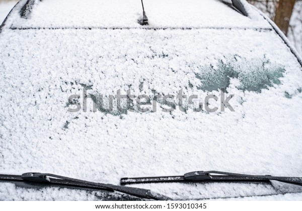 Snow-covered\
automobile glass of the car in the winter.\
