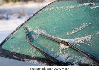Snow-covered car windshield. Wipers and washers in frost. Frost and cars. - Shutterstock ID 2099274487