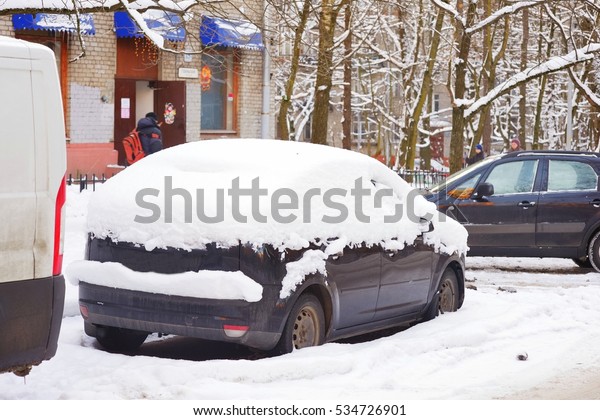 Snow-covered car in the yard. Daily life of\
Russian city streets after a\
snowfall.