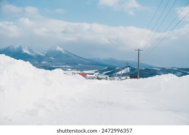 A snow-covered country road in Biei, Hokkaido and mountain background - Powered by Shutterstock