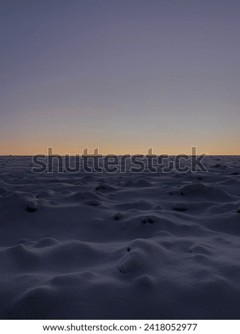 Snow-covered field against the sunset. Natural textures. Natural works of art. Beauty of nature. Creation of nature. Snow waves. Silence. Peace. Place of power. Countryside.