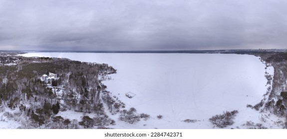 Snow-covered forest on lake shore with ice at sunset and the city on horizon, auerial view. Beautiful winter forest landscape. Lake Shartash and Yekaterinburg, Russia - Powered by Shutterstock