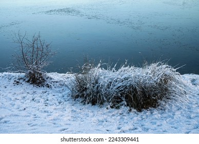 Snow-covered ground on the bank of frozen lake caused by frost days in December - Powered by Shutterstock