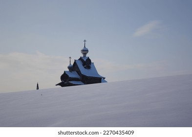 snow-covered hill against the background of part of the building of the old wooden Russian church