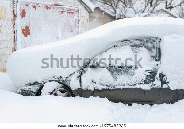 Snow-covered machine. Car under the snow. Lots of\
snow and big snowdrifts on the street. Vehicles are completely\
covered in snow. Cold winter\
weather