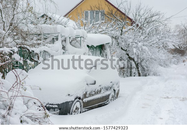 Snow-covered machine. Car under the snow. Lots of\
snow and big snowdrifts on the street. Vehicles are completely\
covered in snow. Cold winter\
weather