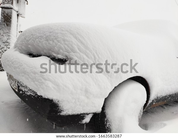 Snow-covered machine. Car\
under the snow. Lots of snow and big snowdrifts on the street. Cold\
winter weather