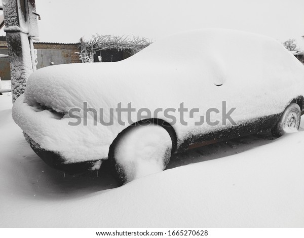 Snow-covered machine. Car\
under the snow. Lots of snow and big snowdrifts on the street. Cold\
winter weather