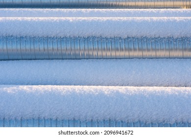 Snow-covered metal pipes.  Venting pipes outside.
