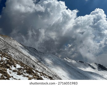 Snow-covered mountain landscape under a dramatic cloudy sky, showcasing natural beauty and serene outdoor scenery.
