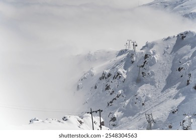 Snow-Covered Mountain Peaks with Cable Cars in Misty Winter Landscape - Powered by Shutterstock