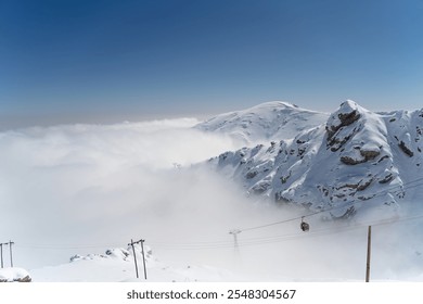 Snow-Covered Mountain Peaks with Cable Cars in Misty Winter Landscape - Powered by Shutterstock