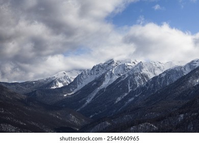 Snow-covered mountain range against dramatic cloudy blue sky