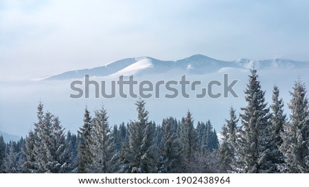Snow-covered mountain range amid clouds.