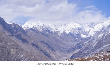 Snow-covered Mountains forming a tranquil valley, where pristine snow contrasts with rugged peaks, creating a serene and majestic winter landscape. - Powered by Shutterstock