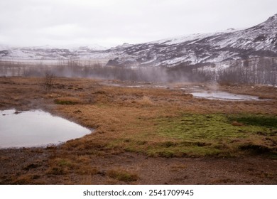 Snow-covered mountains and misty landscape with reflective water pools. - Powered by Shutterstock