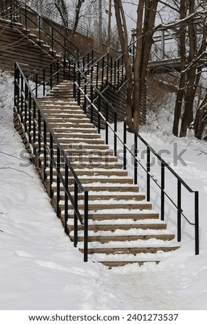 Snow-covered outdoor staircase in black steel. Some trees in background. GoranOfSweden