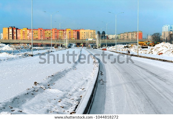 Snow-covered road to the city.\
Road junction overpass. High-rise buildings in the winter in the\
snow.