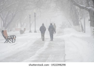 A snow-covered road with people in a storm,blizzard or snowfall in winter in bad weather in the city.Extreme winter weather conditions in the north.People walk through the streets under heavy snowfall - Shutterstock ID 1922398298