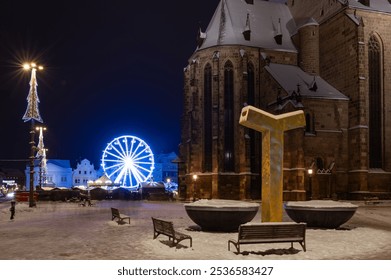 Snow-covered square illuminated by festive lights with a church, a ferris wheel, and benches at night in a winter wonderland - Powered by Shutterstock