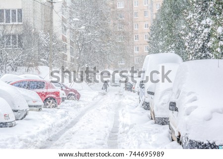 Snow-covered street and cars with a lonely pedestrian. Heavy snowstorm