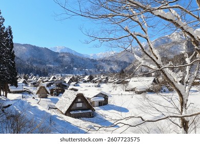 Snow-covered traditional Japanese village of Shirakawa-go, nestled in the mountains with Gassho-style thatched roof houses. A peaceful winter landscape under a clear blue sky, perfect for travel and n