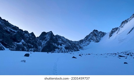 A snow-covered trail leading to the Delaunay Pass. Dawn in the Altai mountains. Climbing Mount Belukha. Beautiful morning mountain winter landscape. Amazing natural background.