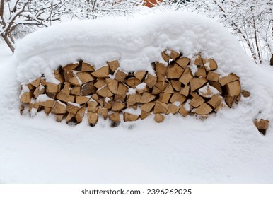 Snow-covered tree, firewood in  during snowfall. Stacked firewood.  - Powered by Shutterstock