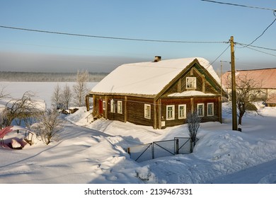 Snow-covered village in winter Russia, wooden country house on roof of which snow lies.