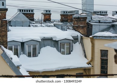 Snow-covered Windows In The Attic Apartment, Roof Leak, Roof Cover Damage, High Precipitation, Danger Of Falling Snow On A Person, Roof Is Covered With Snow, Old Chimneys, Winter Season Concept.