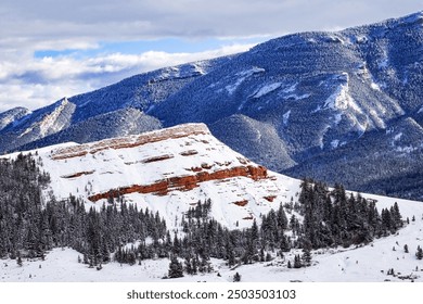 Snow-covered winter landscape of O'Hara Mountain and red chugwater rock formation in the foreground with evergreen trees at the rock base in northwest Wyoming, USA - Powered by Shutterstock