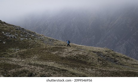 SNOWDONIA, UK - 2021: A Hiker Walking A Mountain Ridge In The Mountains Of Snowdonia Wales UK