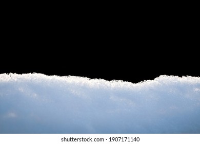 Snowdrift, isolated on black background. Fluffy snow edge at winter sunny day on black background.