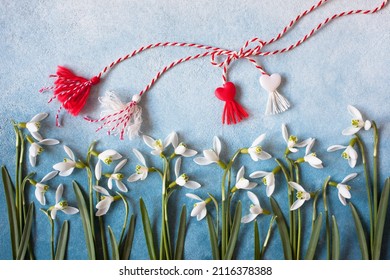 Snowdrop flowers and a red and white symbol of the holiday of March 1 on a colorful white and blue background. Postcard for the holiday Martenitsa, Baba Marta, concept.