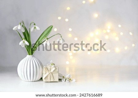 snowdrops flowers and gift box on table, abstract light background. white snowdrops, symbol of spring season. romantic gentle nature image. hello spring, 8 march, Mother's day concept. copy space