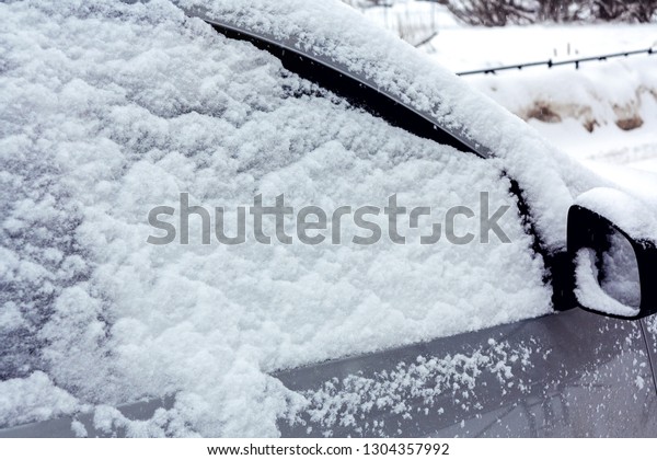 Snowfall in\
the city, part of the car covered by\
snow