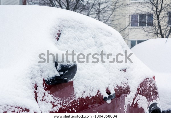Snowfall in
the city, part of the car covered by
snow