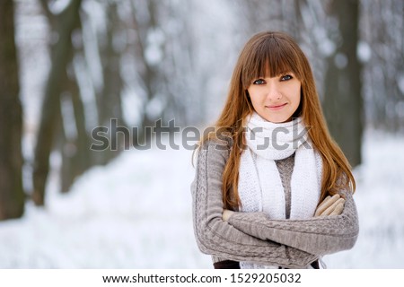 Snowfall in the forest, the girl smiles and poses, a beautiful winter, a great New Year mood, a cute woman froze slightly