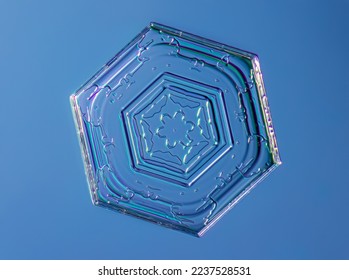 Snowflake on smooth gradient background. Macro photo of real snow crystal on glass surface. This is small snowflake crystal with unusual pattern