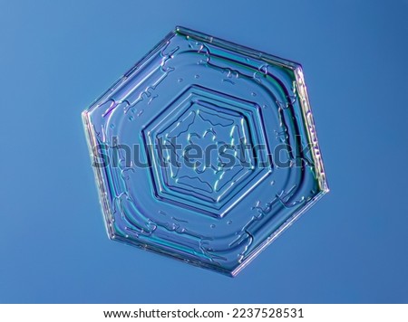 Snowflake on smooth gradient background. Macro photo of real snow crystal on glass surface. This is small snowflake crystal with unusual pattern