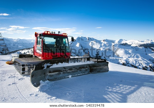 Snow-grooming machine on snow hill ready\
for skiing slope preparations in Austrian\
Alps.