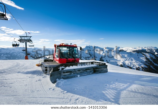 Snow-grooming machine on snow hill ready\
for skiing slope preparations in Austrian\
Alps.