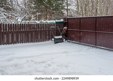 It's snowing outside and there's a snow removal tool in the corner in the yard - Powered by Shutterstock